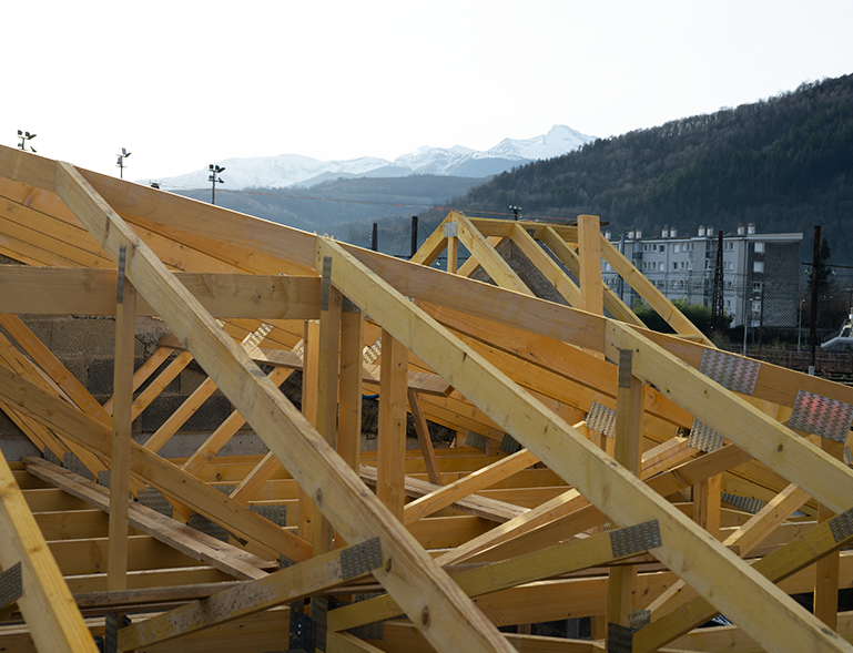 Charpente de toit en bois avec pièces et assemblages visibles sur chantier de construction