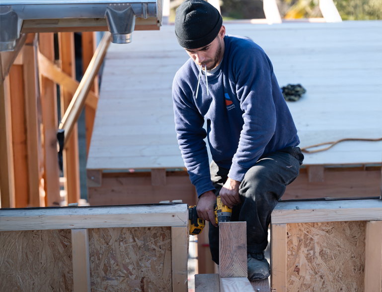 charpentier Troyano Charpente vissant un panneau OSB sur ossature bois de construction neuve
