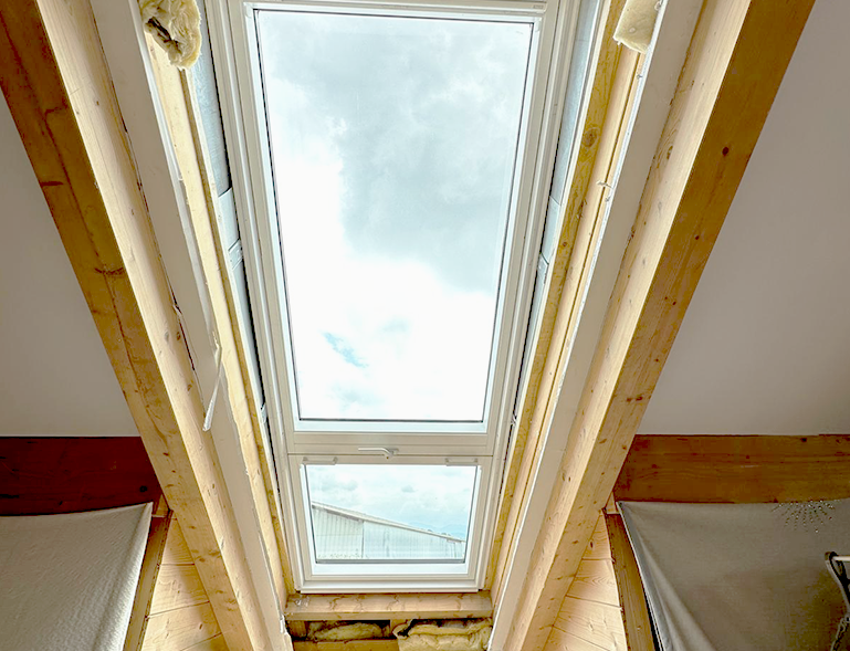 pose d'une fenêtre de toit Velux vue depuis l'intérieur avec isolation laine de verre sur charpente bois